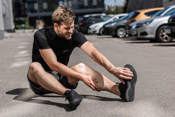 muscular bearded sportsman with leg injury on street - Zdjęcie, obraz