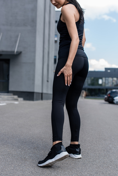 cropped view of sportswoman in black sneakers on street - Foto, Imagen
