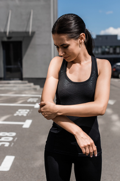 sportswoman with elbow pain on street in sunny day - Valokuva, kuva