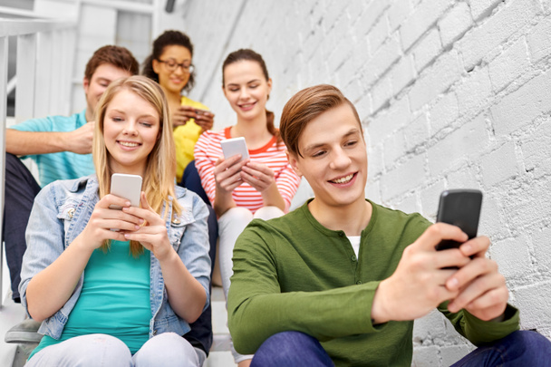 Schüler mit Smartphones sitzen auf Treppe - Foto, Bild