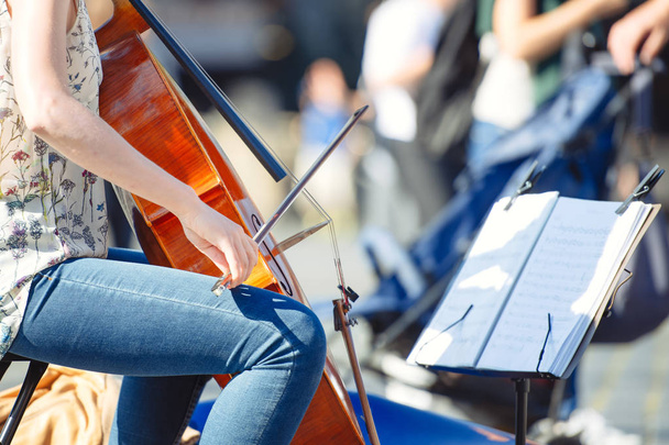 Jugador de violonchelo en la calle entre la gente
 - Foto, Imagen