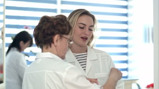 Enfermera mayor llevando documento médico a enfermera joven y médico varón
 - Imágenes, Vídeo