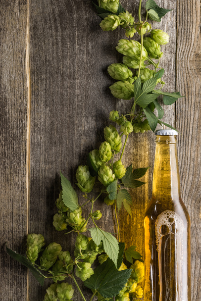 vista superior de la cerveza en botella con lúpulo verde en mesa de madera
 - Foto, Imagen