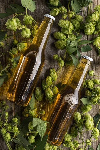 top view of beer in bottles with green hop on wooden table - Zdjęcie, obraz