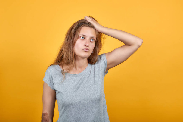 brunette meisje in grijs t-shirt over geïsoleerde oranje achtergrond toont emoties - Foto, afbeelding