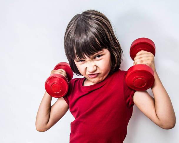 mad frowning child expressing rage and violence with bully dumbbells - Valokuva, kuva