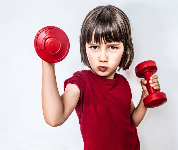 portrait of cheeky pouting child raising dumbbells for feminism - Foto, immagini