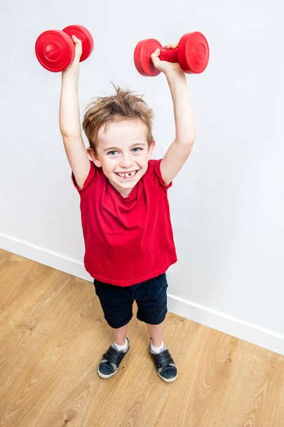 happy boy enjoying lifting up weights winning to express success - Фото, изображение