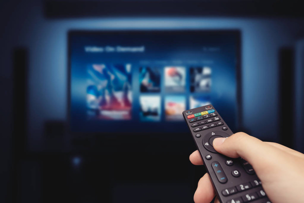 VOD service screen with remote control in hand - Foto, immagini