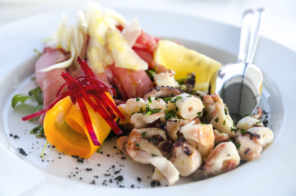 Салат из морепродуктов подается в белой тарелке крупным планом. Осьминог и тунец фи
 - Фото, изображение