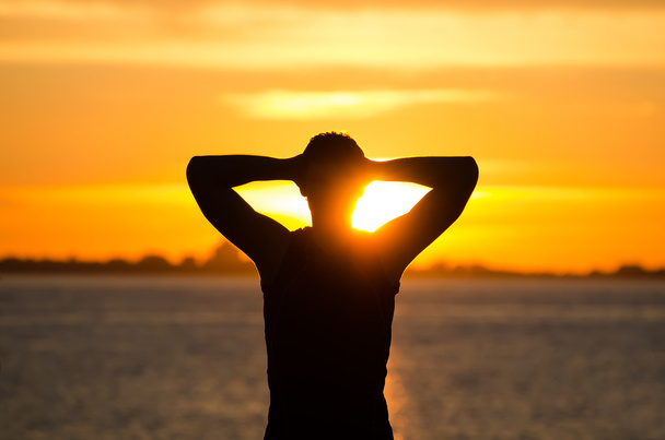 Ihminen lepää rannalla auringonnousun aikaan
 - Valokuva, kuva
