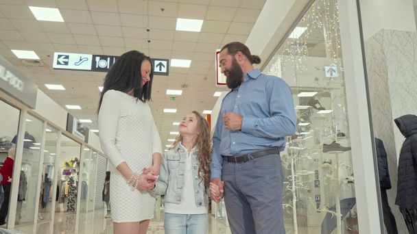 Érett házaspár és aranyos lánya élvezi bevásárlás veszi a bevásárlóközpontban - Fotó, kép