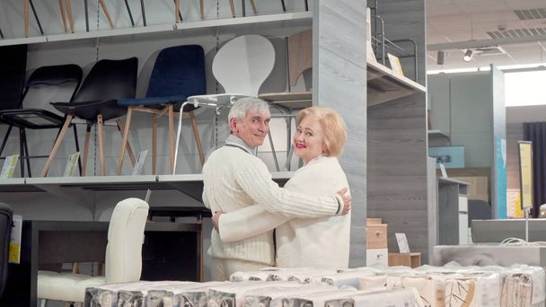 Rückansicht eines schönen Senioren-Ehepaares, das im Geschäft gemeinsam Möbel aussucht - Foto, Bild