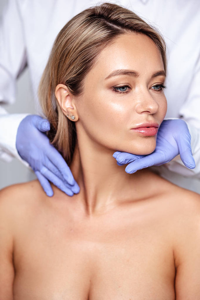 Close up portrait of young blonde woman with cosmetologyst hands in a gloves. Preparation for operation or procedure. Perfect skin, spa and care - Φωτογραφία, εικόνα