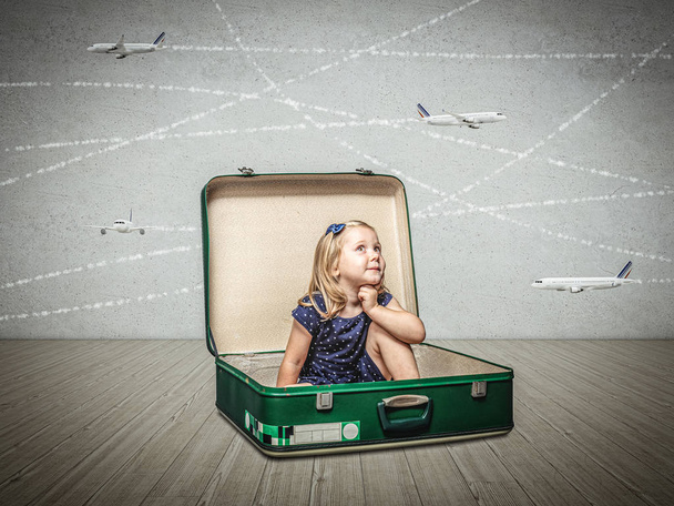 pieni tyttö istuu vanhan matkalaukun sisällä kuvittelee seikkailuja
  - Valokuva, kuva