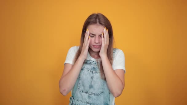 Молода жінка в білій футболці на помаранчевому фоні показує емоції
 - Кадри, відео