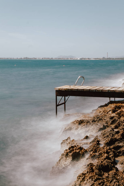 Alcanada beach with wooden ports overlooking the port of Alcudia. Sea enraged against the wooden port. - Zdjęcie, obraz