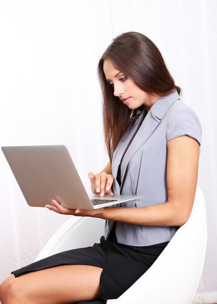Young beautiful business woman with laptop in office - 写真・画像