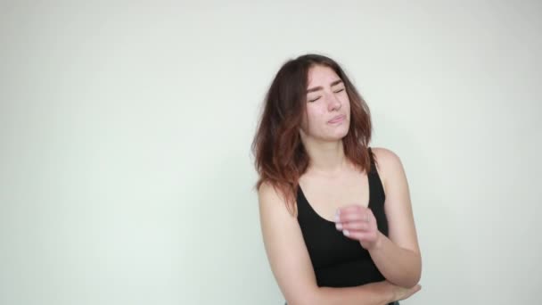 mooi meisje in zwarte tank top over geïsoleerde witte achtergrond toont emoties - Video