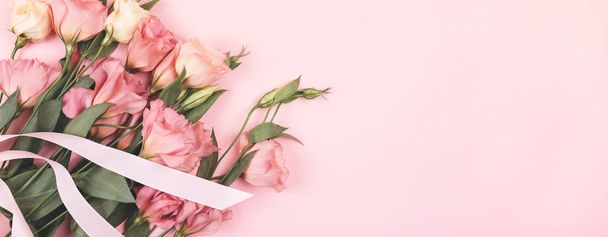 Mooie bloemen op een delicate roze textuur, lint op een boeket. Eustoma. achtergrond voor uw vakantie ontwerp - Foto, afbeelding