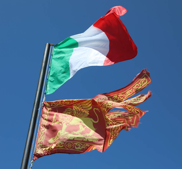 Twee vlag op de wind een Italiaanse en een van de regio Veneto - Foto, afbeelding