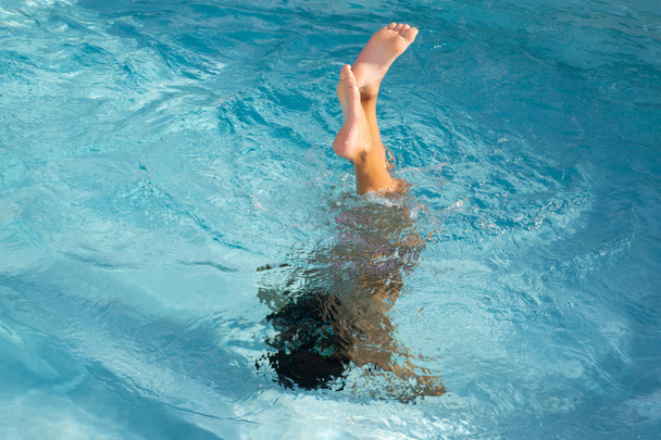 夏休みに青いスイミングプールで水中で遊んで楽しんでいる水しぶきの少年の男の子 - 写真・画像