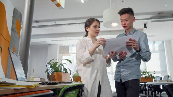 zwei junge Unternehmer beim Durchblättern von Papieren im Büro - Foto, Bild