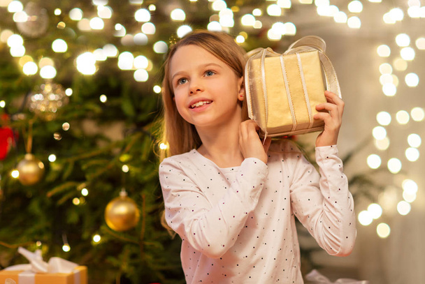 lächelndes Mädchen mit Weihnachtsgeschenk zu Hause - Foto, Bild