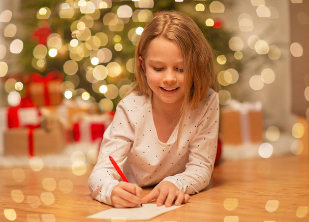 smiling girl writing christmas wish list at home - Fotó, kép