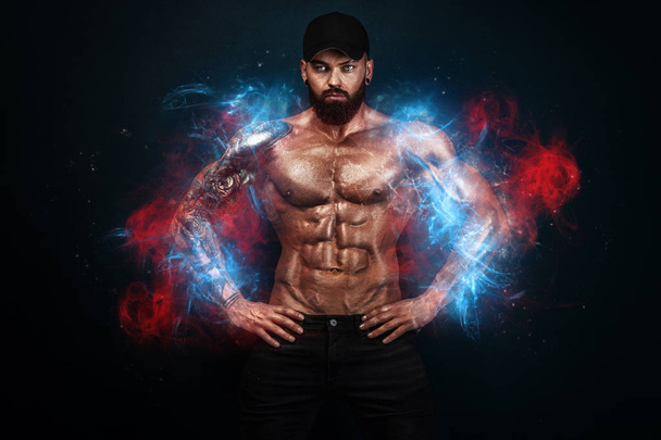 Strong and fit man bodybuilder. Sporty muscular guy. Spot and fitness motivation. Man on fire like a phoenix. - Foto, afbeelding
