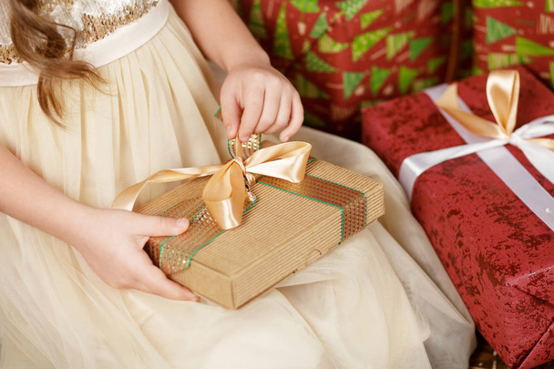 Piękna dziewczynka otwierający pudełko na prezent bożonarodzeniowy. Boże Narodzenie an - Zdjęcie, obraz