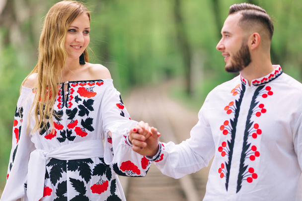 Newlyweds in embroidered clothes are holding hands and walking i - Foto, Bild