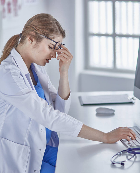 Young female doctor tired after working with computer - Φωτογραφία, εικόνα