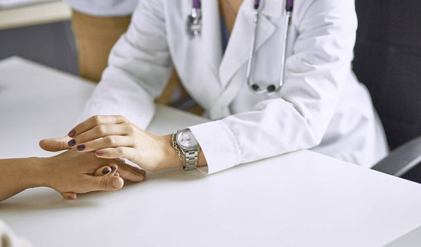 Mujer médico calma paciente y toma de la mano
 - Foto, imagen