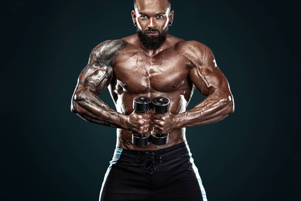 Strong and fit man bodybuilder. Sporty muscular guy with dumbbells. Spot and fitness motivation. - Foto, afbeelding