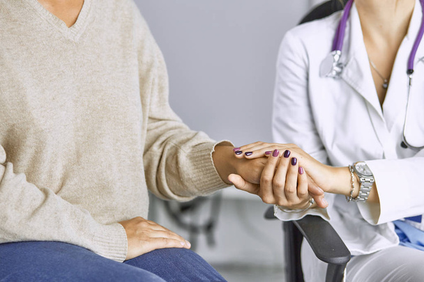 Ärztin beruhigt Patientin und hält Hand an - Foto, Bild