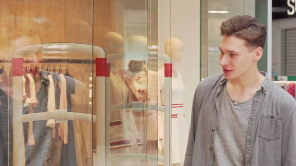 Mladý muž zkoumáním oblečení na displeji obchodu v nákupním středisku - Fotografie, Obrázek