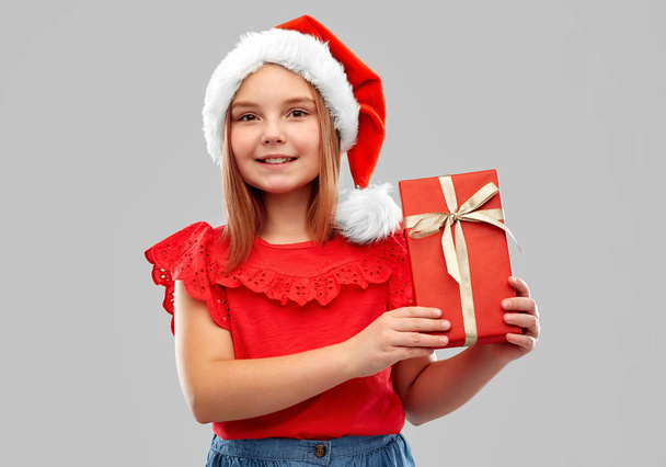 smiling girl in snata hat with christmas gift - 写真・画像