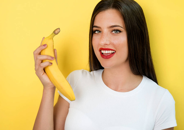 woman holding banana on yellow background - Foto, Imagem