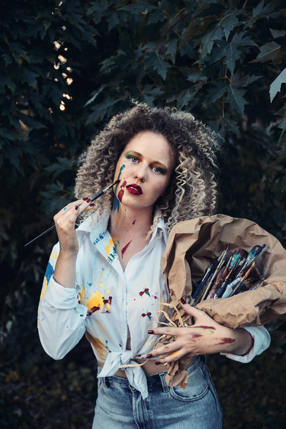 Young woman artist holding brushes outdoors - 写真・画像