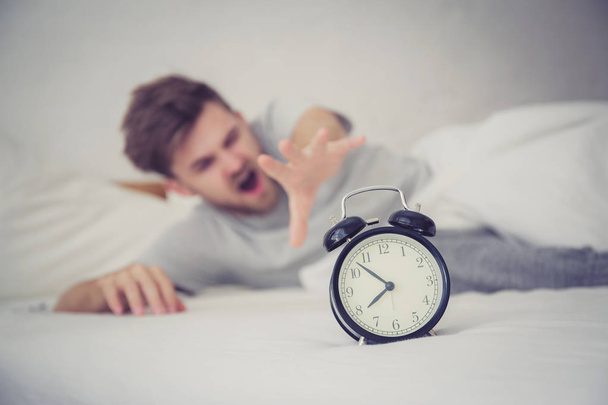 man sleepy nationality american reaching for the alarm clock sle - Фото, изображение