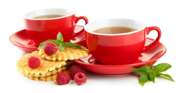 Cups of tea with cookies and raspberries isolated on white - 写真・画像