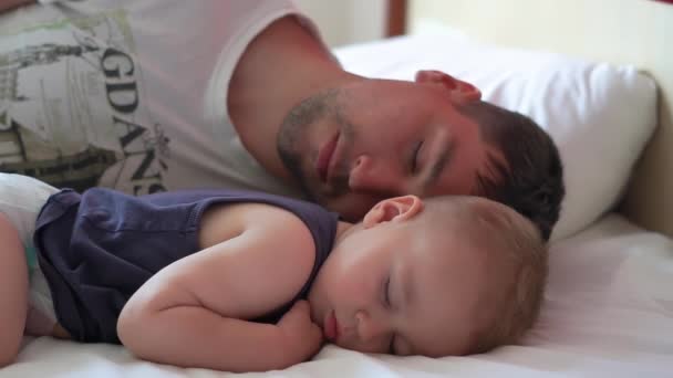 Unavený mladý táta s dítětem sladce spí ve velké posteli v pomalém pohybu - Záběry, video
