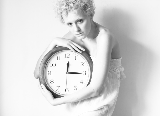Scrawny blond girl with big clock in hands - Foto, afbeelding