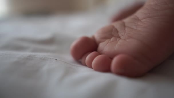 Kleine baby foot shot close up, die op het bed in slow motion ligt - Video