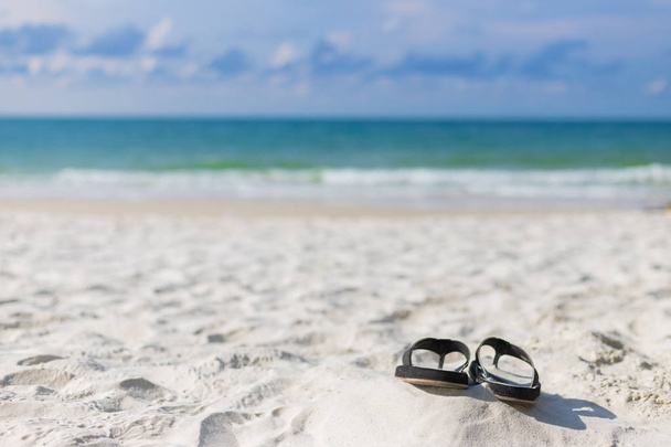 Koncept letních prázdnin. Černý pár sandálů na pláži.  - Fotografie, Obrázek