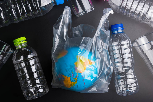 Γήινη παγκόσμια σφαίρα και πλαστικά απορρίμματα μπουκαλιών στον μαύρο προγρού - Φωτογραφία, εικόνα