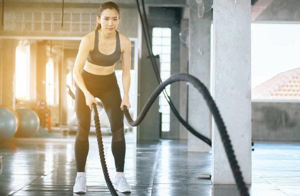 Strong and slim woman using battle rope at gym,Female doing exercise in functional training  - 写真・画像