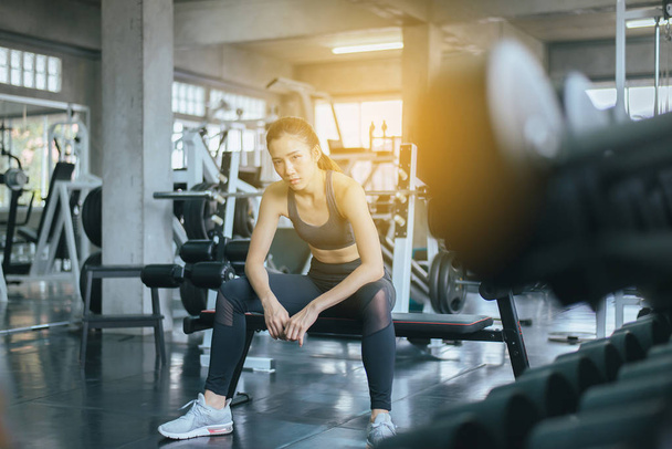Fit asian woman sitting and relax after the training session in gym,Concept healthy and lifestyle,Female taking a break after exercise and workout - 写真・画像