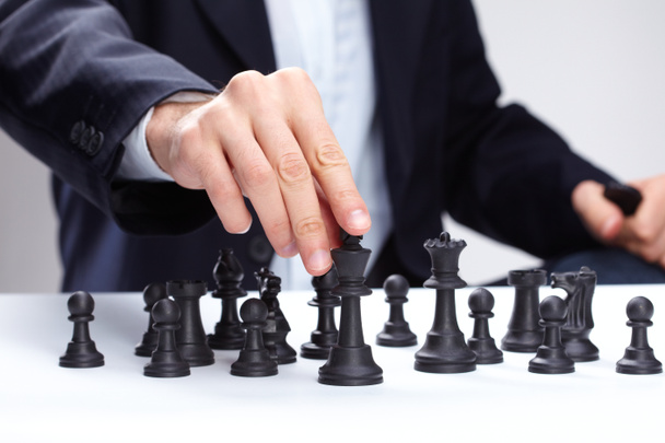 Liikemies liikuttaa shakkihahmoa
 - Valokuva, kuva